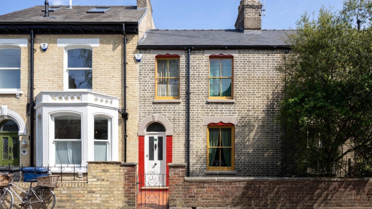 Exterior of David Parr House, a small terraced home featuring a white front door framed by red-painted brickwork, and with red-painted window sashes